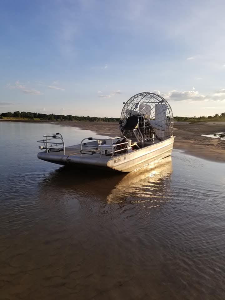 Aluminum airboat in shallow Red River water—prop in a cage, open bow, suited to skinny water and current below Denison Dam.